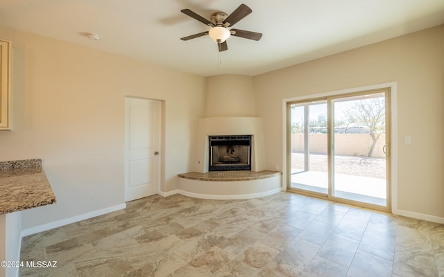 unfurnished living room featuring a large fireplace and ceiling fan