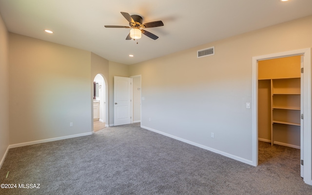 unfurnished bedroom featuring carpet flooring, a walk in closet, a closet, and ceiling fan