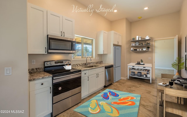 kitchen with white cabinetry, light stone counters, appliances with stainless steel finishes, and sink