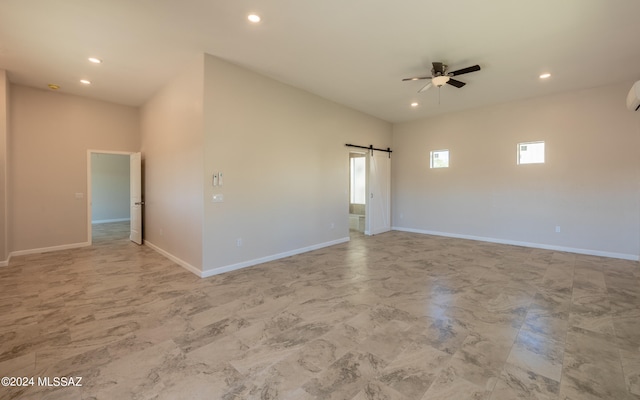 empty room with ceiling fan and a barn door