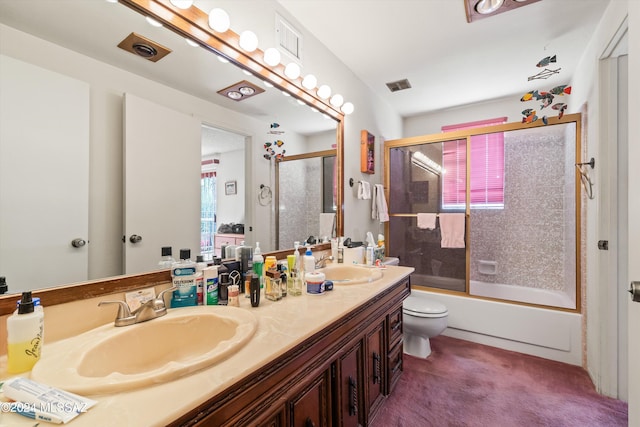 full bathroom featuring vanity, bath / shower combo with glass door, and toilet