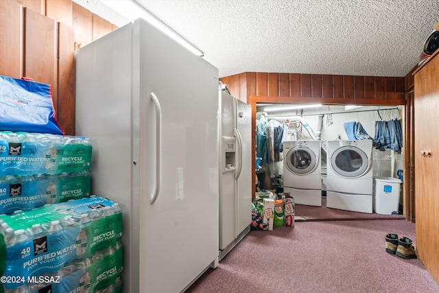 clothes washing area with a textured ceiling, wooden walls, and washing machine and clothes dryer