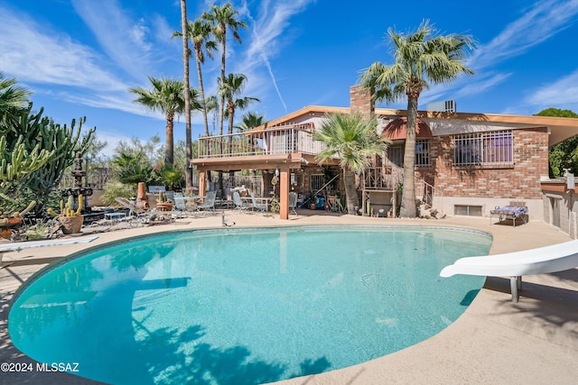 view of pool with a water slide and a patio