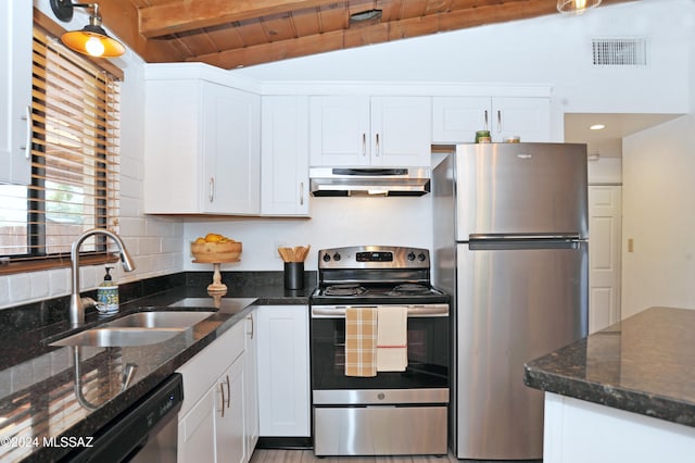 kitchen with white cabinets, appliances with stainless steel finishes, vaulted ceiling with beams, sink, and ventilation hood