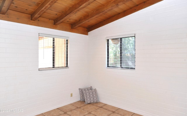 empty room with brick wall, tile patterned floors, lofted ceiling with beams, and wooden ceiling