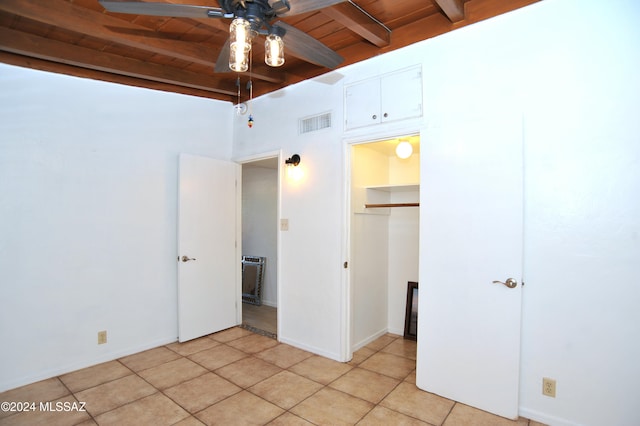 unfurnished bedroom with wood ceiling, a closet, beamed ceiling, light tile patterned floors, and ceiling fan