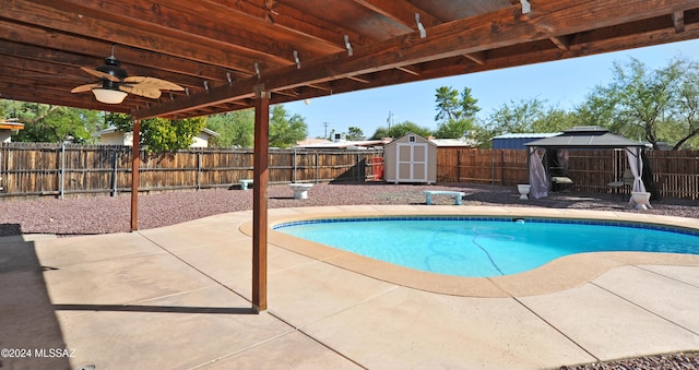 view of pool featuring a gazebo, a shed, a patio area, and ceiling fan