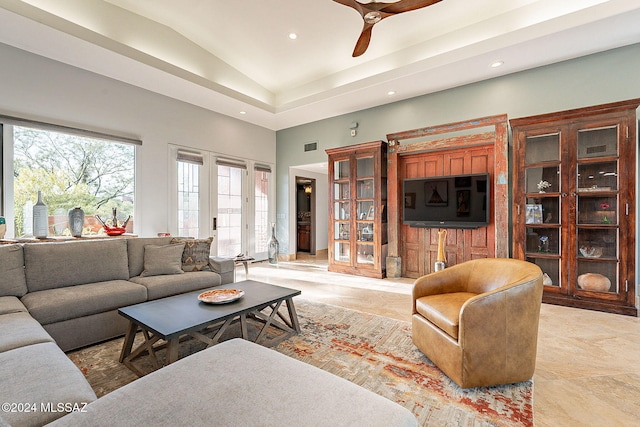 living room featuring a raised ceiling and ceiling fan