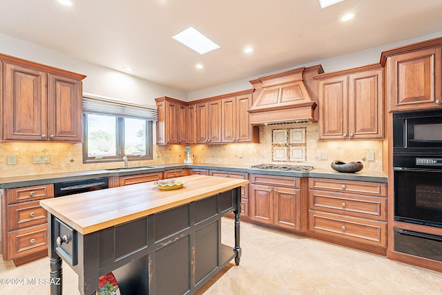 kitchen with black appliances, sink, butcher block counters, a center island, and premium range hood