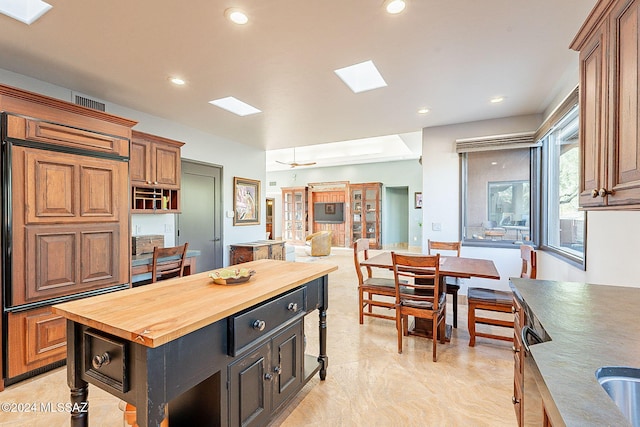 kitchen with a kitchen island, butcher block countertops, a skylight, and ceiling fan