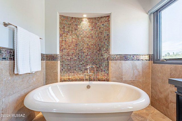 bathroom with tile walls, plenty of natural light, and a bath