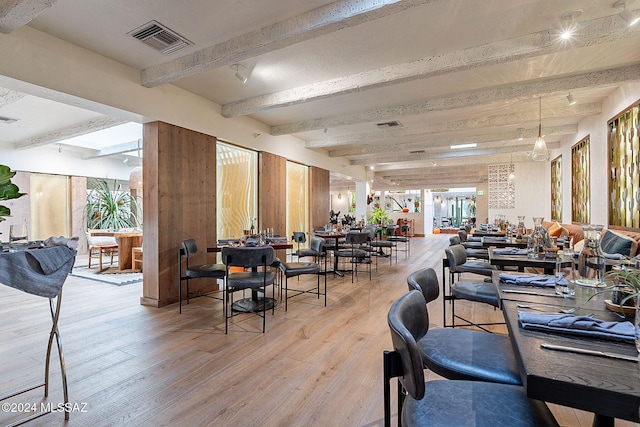 dining space featuring beamed ceiling and light hardwood / wood-style flooring