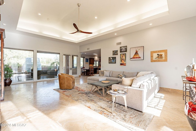 living room featuring ceiling fan and a raised ceiling