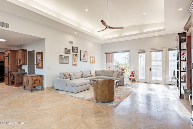 living room with ceiling fan and a raised ceiling