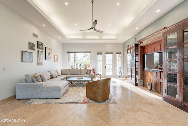 living room with ceiling fan and a tray ceiling