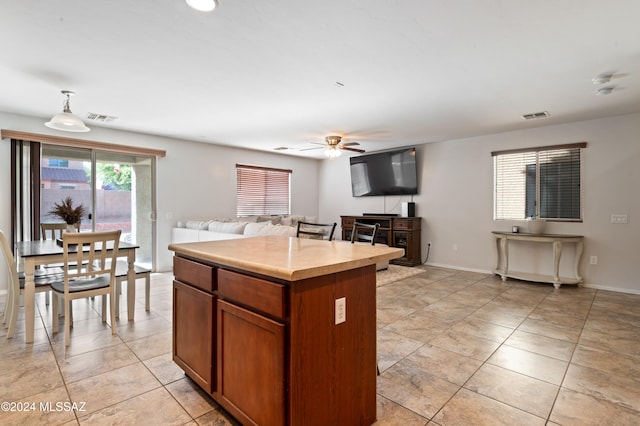 kitchen with ceiling fan, a center island, and decorative light fixtures