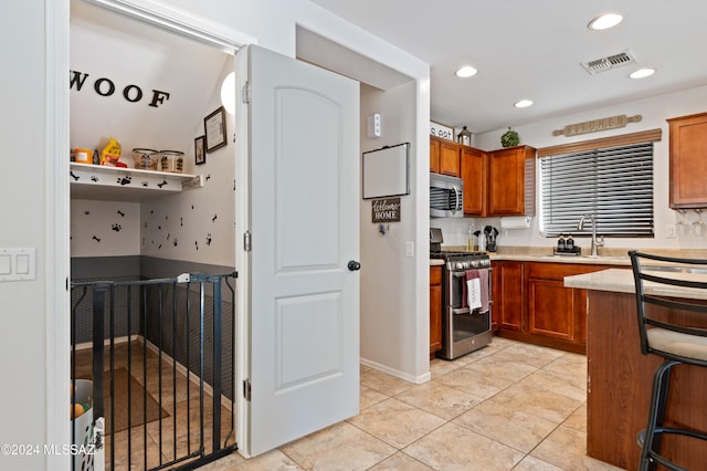 kitchen with stainless steel appliances, sink, a kitchen bar, and light tile patterned floors