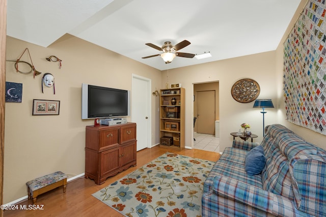 living area featuring light wood-style floors, baseboards, and a ceiling fan