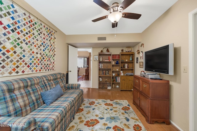 living area featuring light wood-style flooring, visible vents, ceiling fan, and baseboards