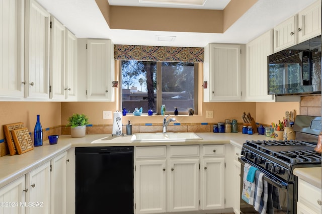 kitchen with black appliances, a tray ceiling, a sink, and light countertops