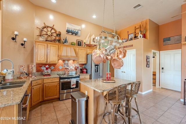 kitchen featuring sink, light stone countertops, light tile patterned flooring, premium range hood, and appliances with stainless steel finishes