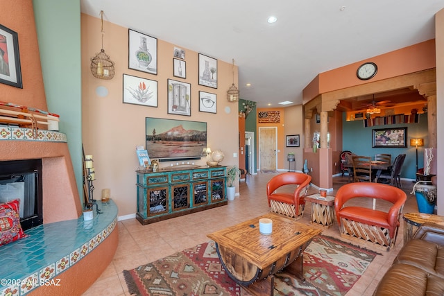 living room featuring decorative columns, light tile patterned floors, and ceiling fan