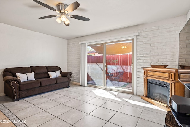 living room featuring a fireplace, light tile patterned flooring, and ceiling fan