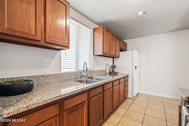 kitchen featuring light tile patterned floors, light stone countertops, and sink