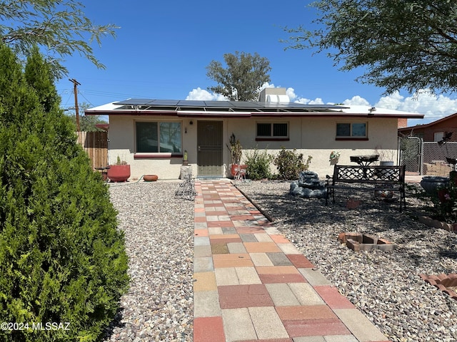 view of front of home featuring a gate, fence, roof mounted solar panels, and stucco siding