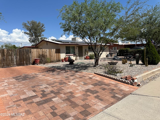 view of front of home featuring roof mounted solar panels and fence