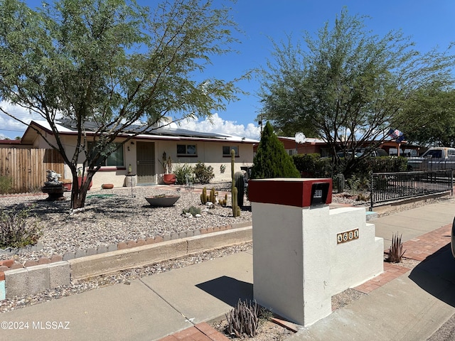 view of front of home featuring a fenced front yard, roof mounted solar panels, and stucco siding