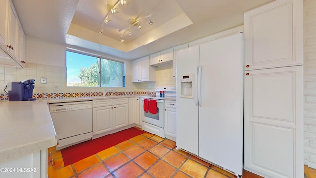 kitchen featuring backsplash, white cabinetry, a tray ceiling, and white appliances