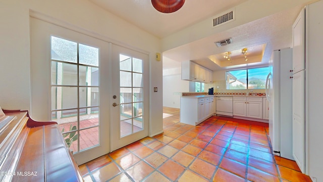 kitchen with white appliances, french doors, plenty of natural light, and white cabinets