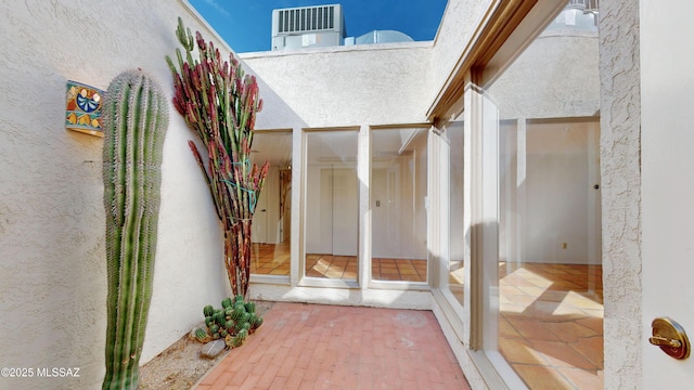 property entrance featuring a patio, central AC unit, and stucco siding