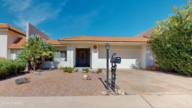 mediterranean / spanish-style home featuring a tile roof, driveway, an attached garage, and stucco siding