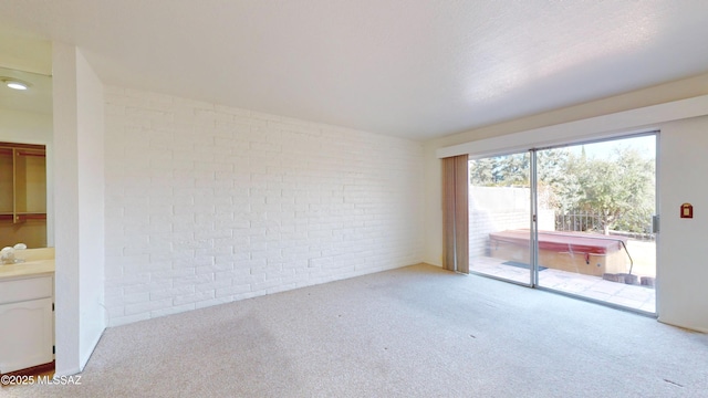 spare room featuring light carpet and brick wall