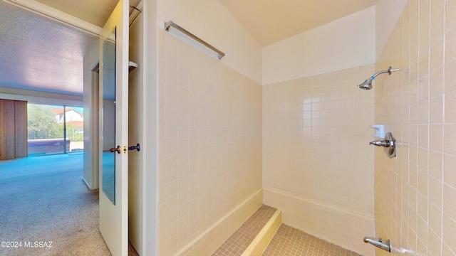 bathroom with a tile shower and a textured ceiling