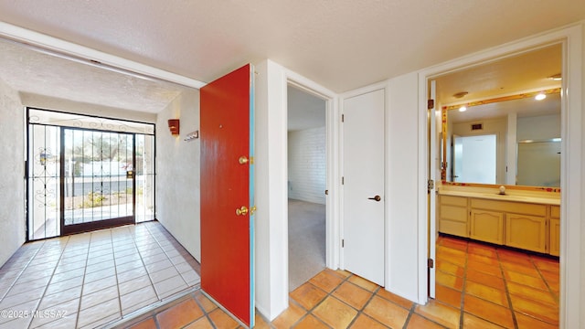 interior space with a sink, a textured ceiling, and light tile patterned floors