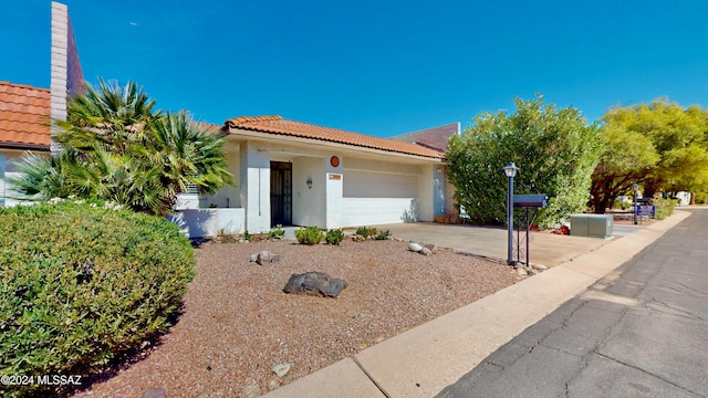 view of front of home with a garage, a tiled roof, concrete driveway, and stucco siding