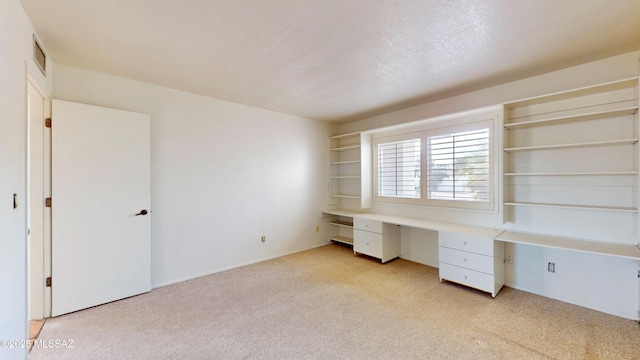 unfurnished office featuring light carpet, visible vents, and built in study area