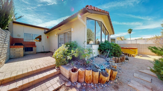 view of side of home featuring a patio area, fence, and stucco siding