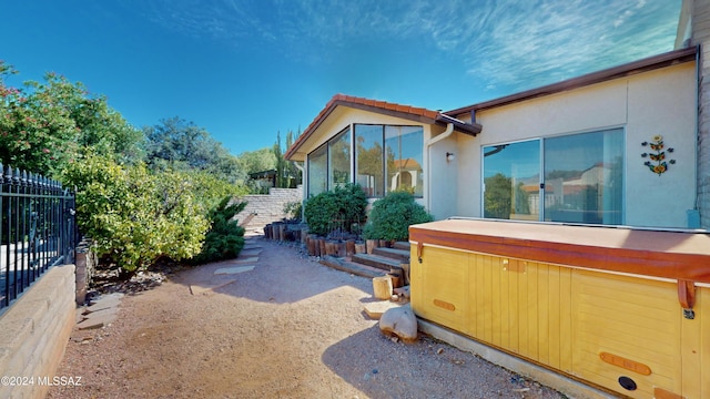 view of side of home with a hot tub, a tile roof, and a fenced backyard