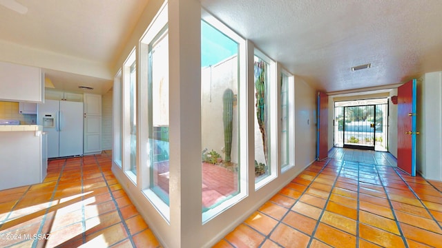 hall featuring a textured ceiling and light tile patterned floors