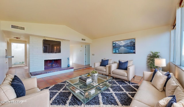 tiled living room with a brick fireplace, visible vents, and vaulted ceiling