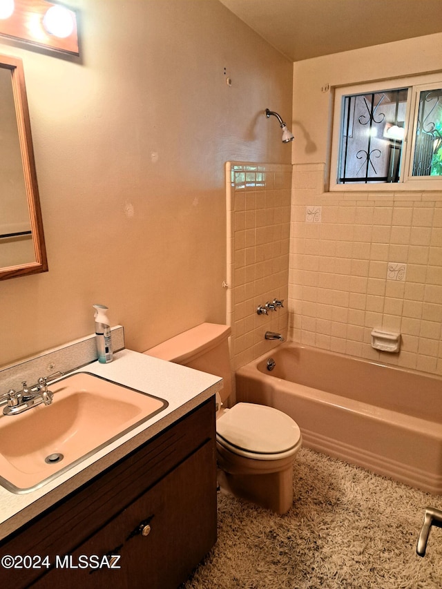 full bathroom featuring tiled shower / bath, vanity, and toilet