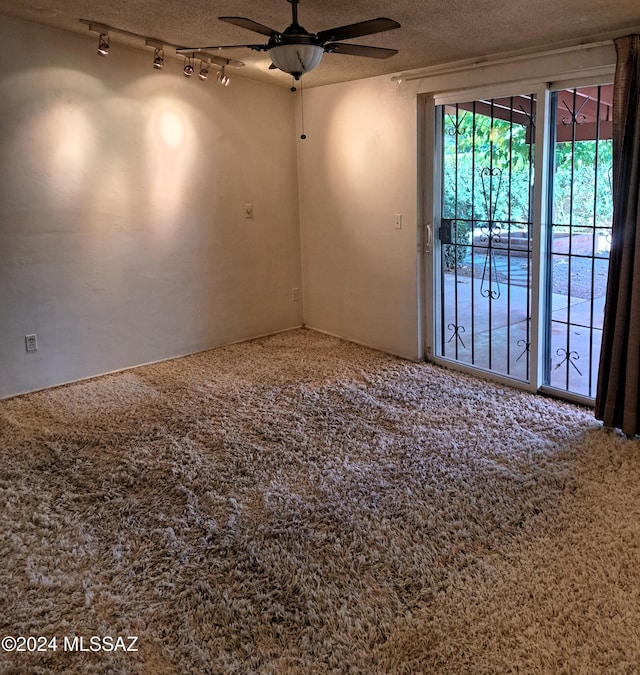 carpeted spare room with ceiling fan, track lighting, and a textured ceiling