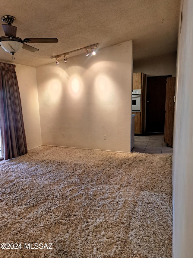 spare room featuring ceiling fan, rail lighting, vaulted ceiling, and a textured ceiling