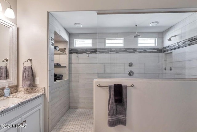 bathroom with vanity, a healthy amount of sunlight, and tiled shower