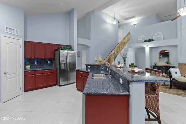 kitchen featuring stainless steel fridge, sink, a high ceiling, and light tile patterned floors