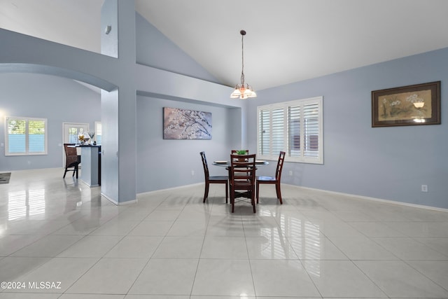 tiled dining area with a notable chandelier, a healthy amount of sunlight, and high vaulted ceiling